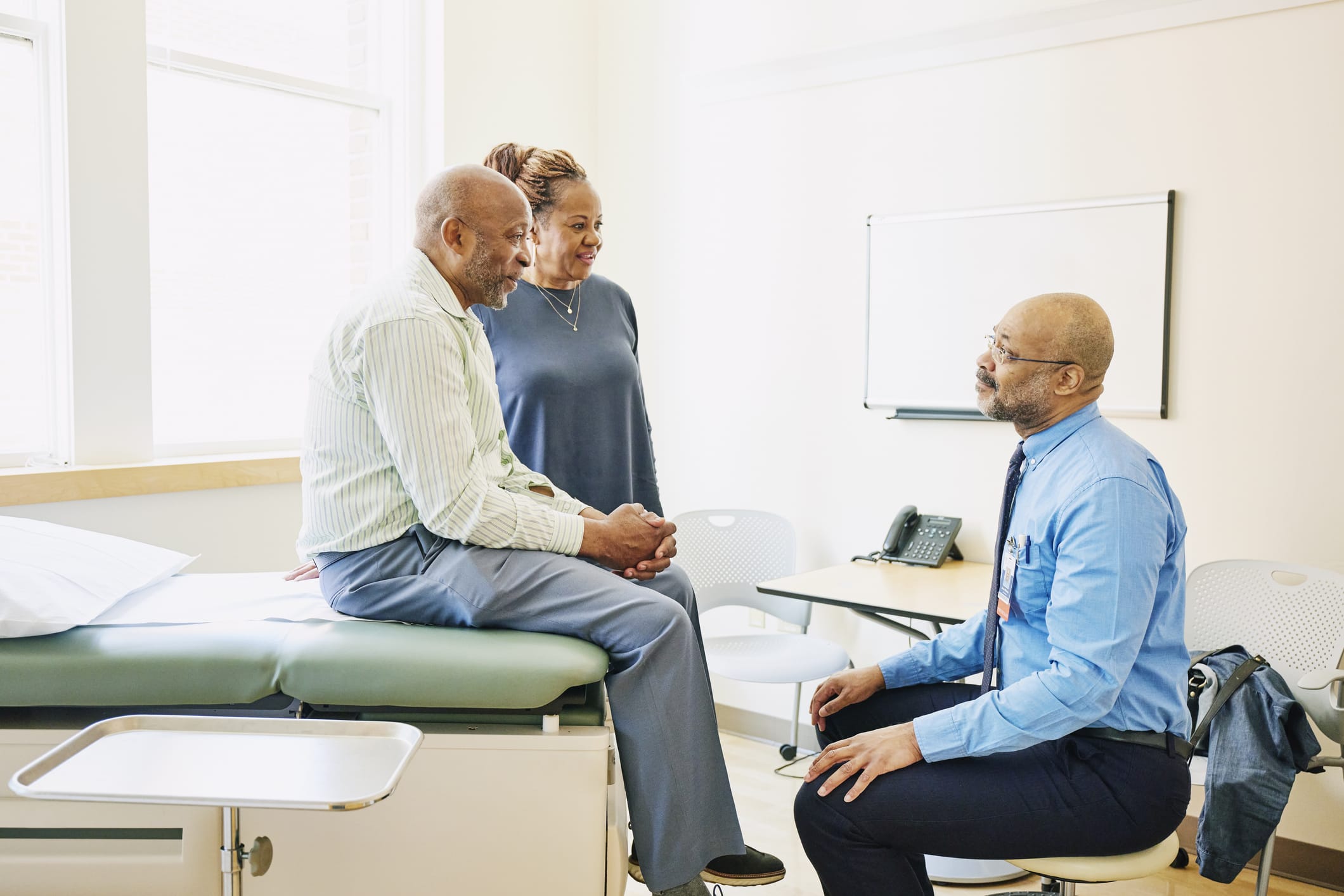 Photo of black patient and wife speaking with doctor during a medical exam