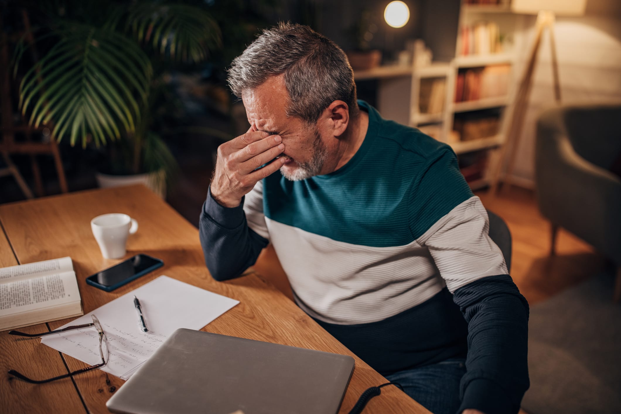 Older man with eye pain pinching face with hand