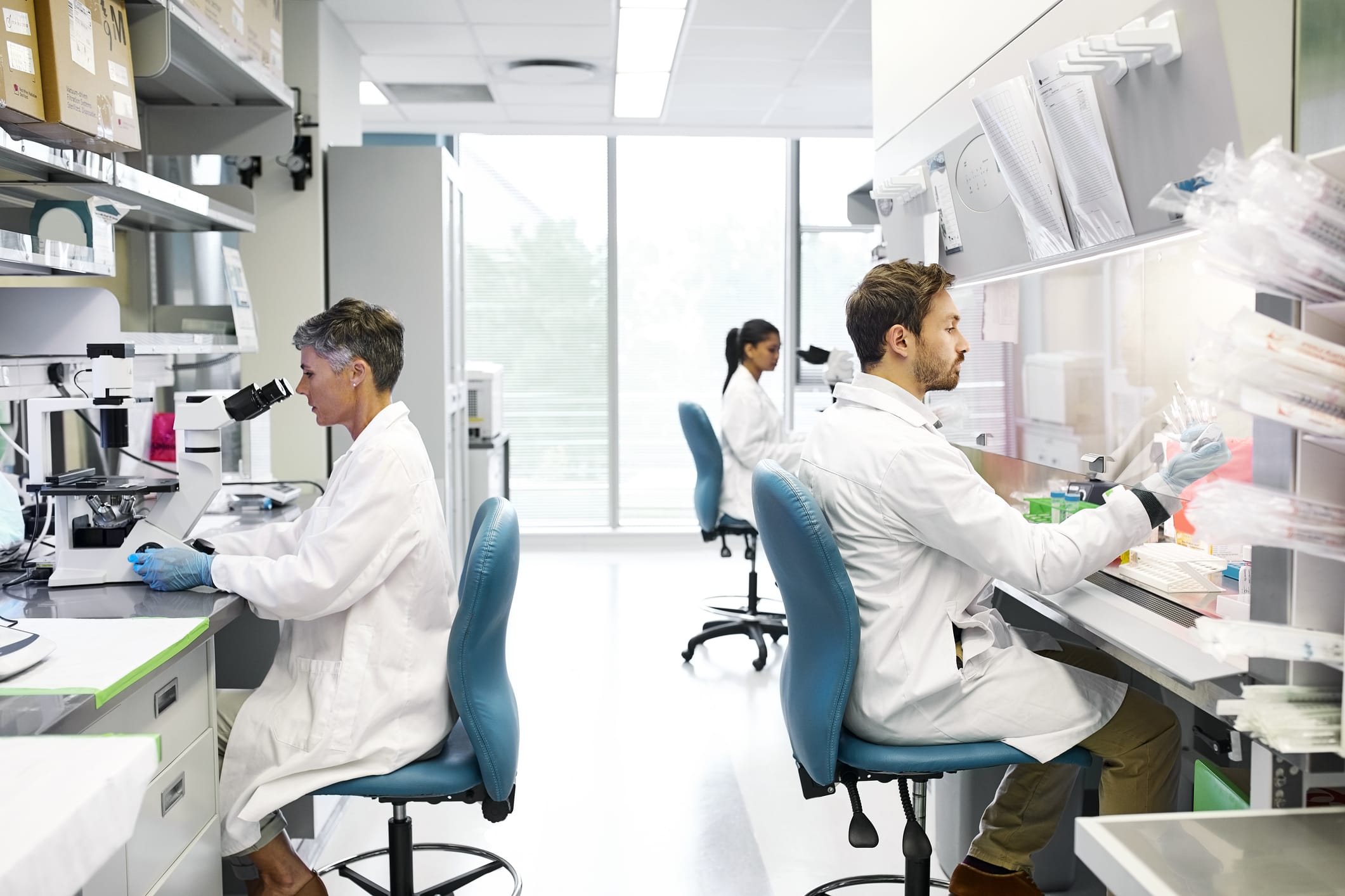 Medical researchers sitting in front of microscopes in a lab
