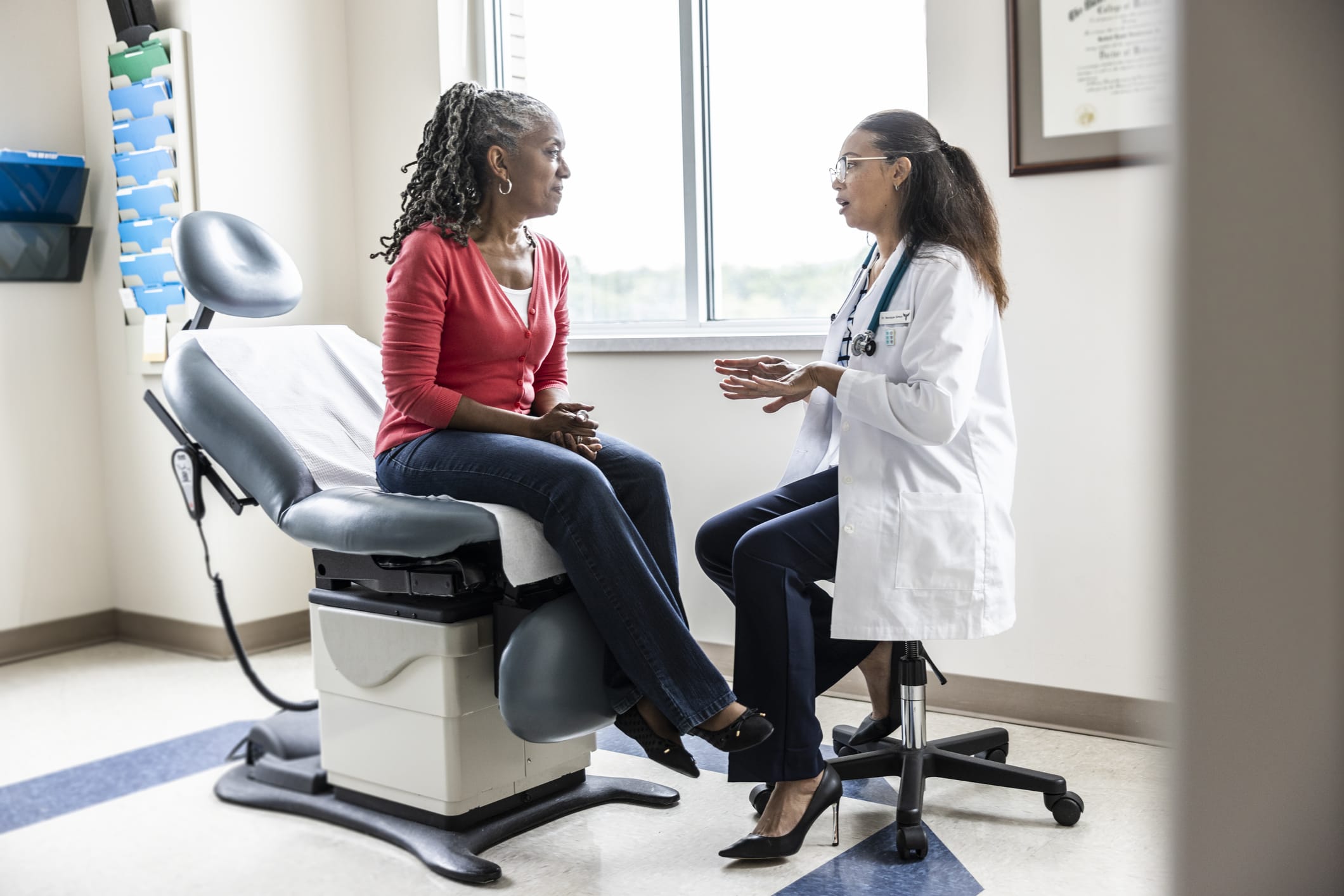Female doctor talking with senior woman in exam room