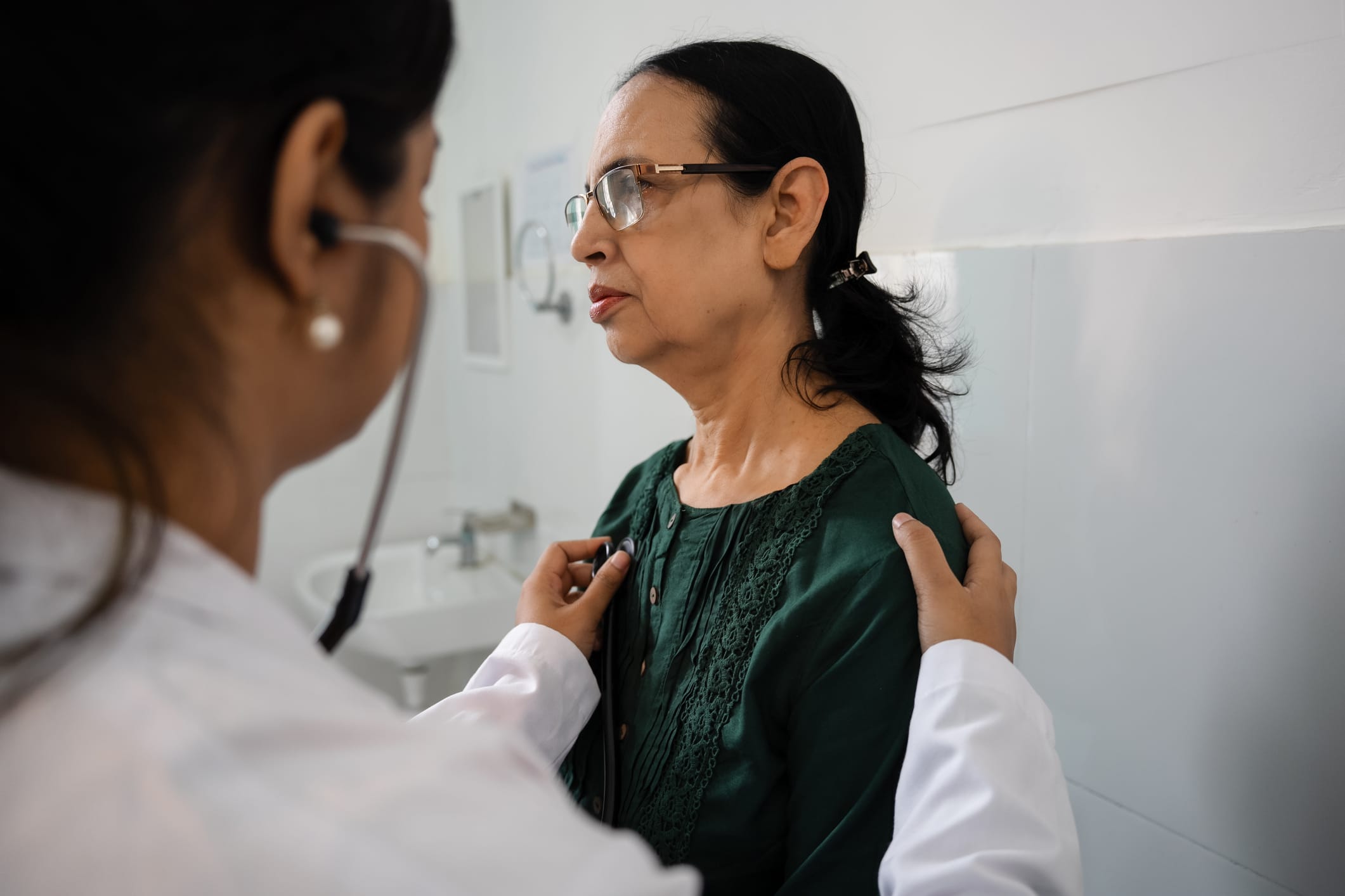 Photo of doctor with stethoscope examining a older woman.