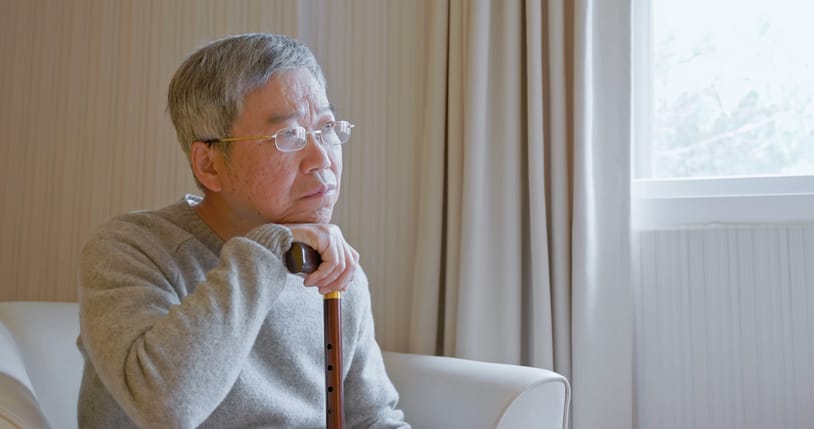 Closeup side view asian elderly male suffer from Dementia - he is sitting on sofa feels so loneliness in bedroom at home