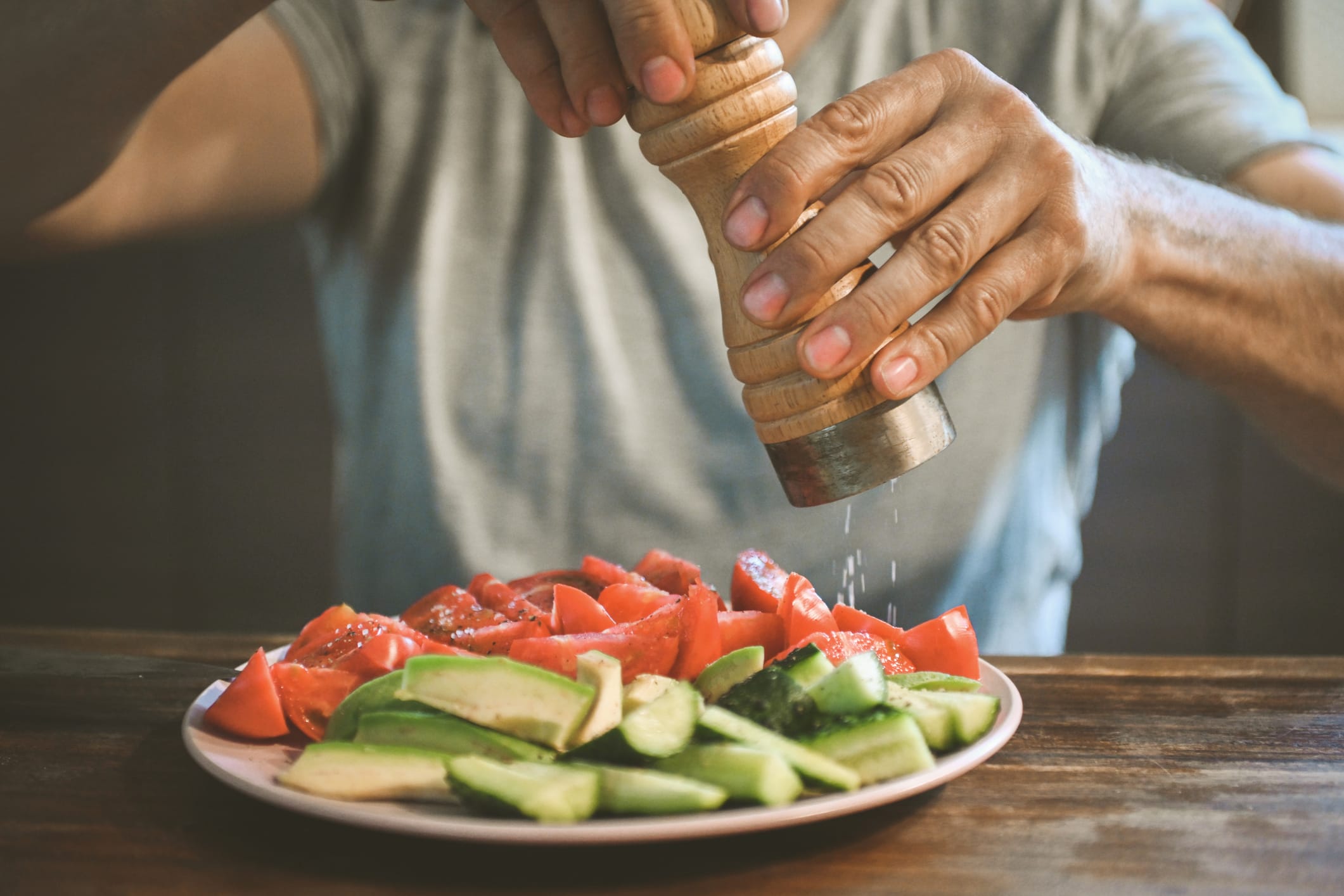 mature adult man salting fresh vegetables and fruits