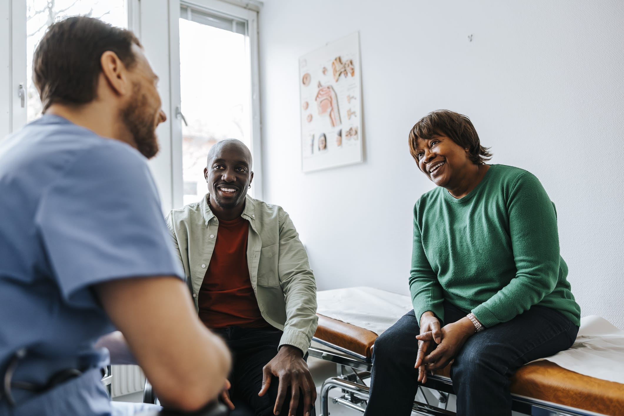 Mother and son sitting with male medical professional during visit in medical examination room
