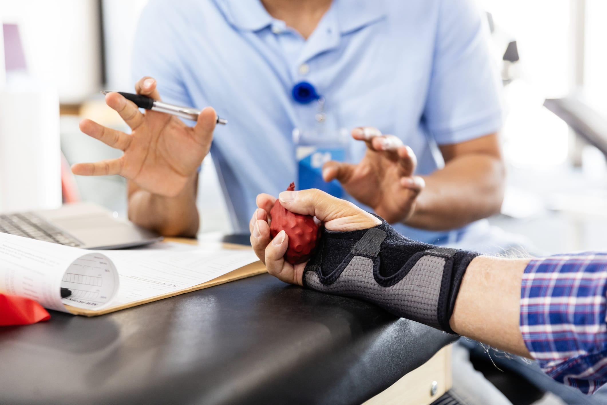 A low angle view of an unrecognizable male occupational therapist as he explains to the unrecognizable senior adult patient how to use a stress ball to strengthen his wrist.