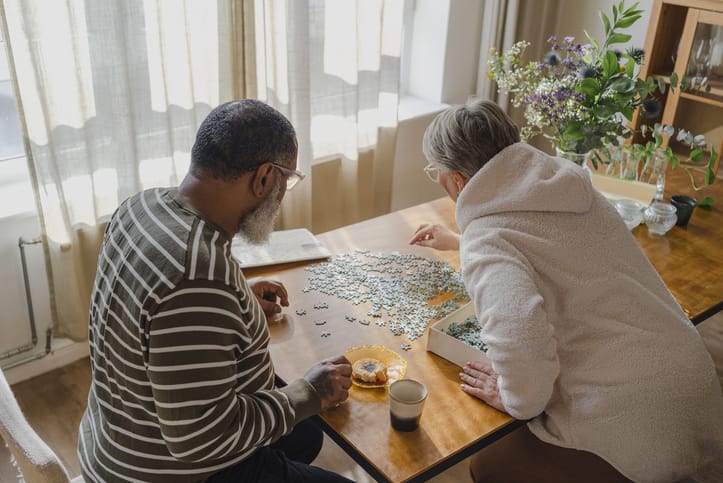 Senior couple doing jigsaw puzzle on table at home