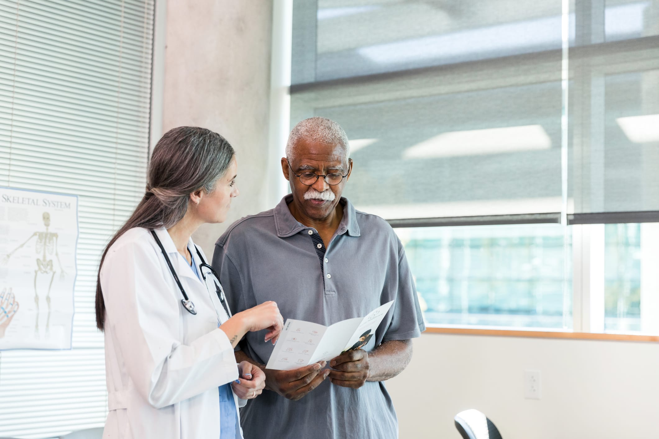 Mature man and female doctor discuss healthcare document.