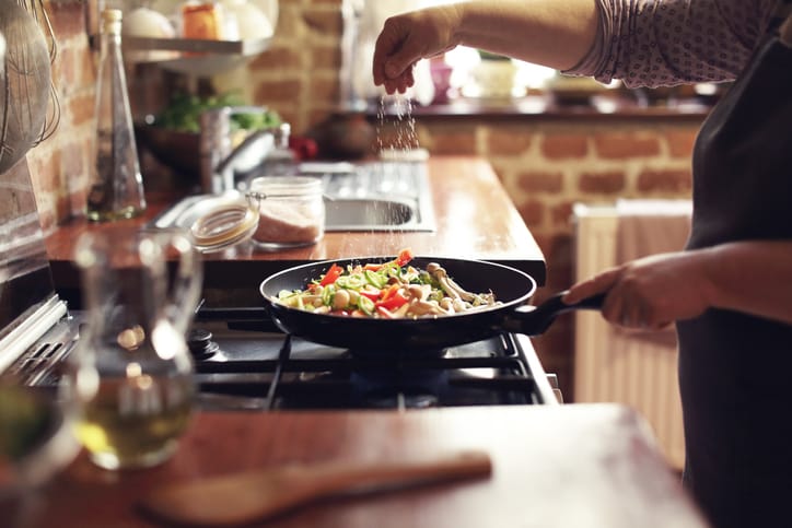 Salting vegetables in a pan on the stove.