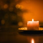 Lit candle against out-of-focus tree lights