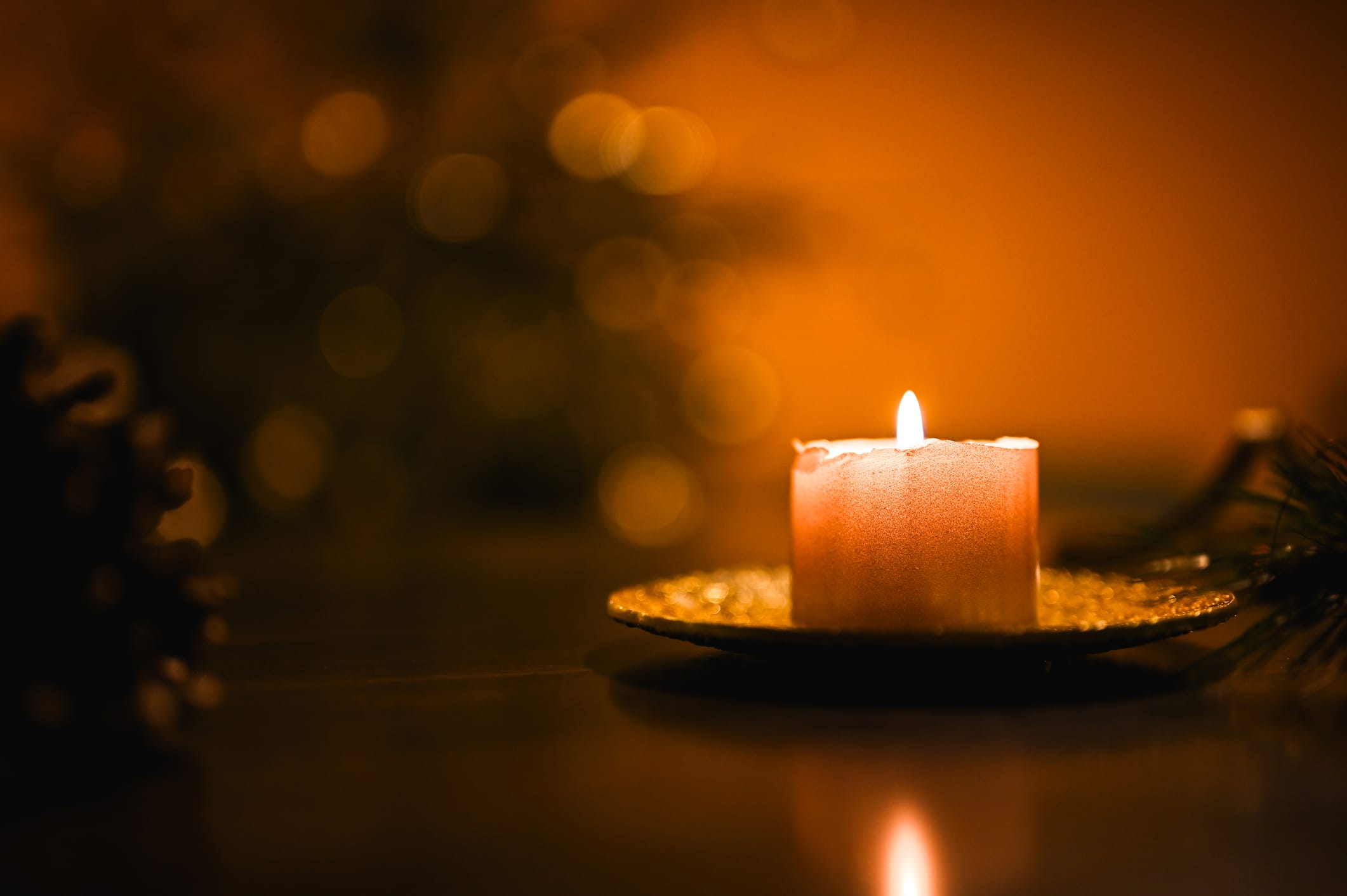 Lit candle against out-of-focus tree lights